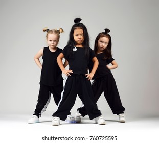Group of three young girl kids hip hop dancers on gray background