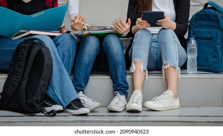 Group Of Three Young Girls College Students Legs And Sneakers Sitting Together In University Campus Outdoor. Concept For Education, Friendship And College Students Life.