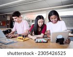 Group of three young students from a technical high school doing a technological team project. People using the computer consulting doubts about their practices in electronic technology class.