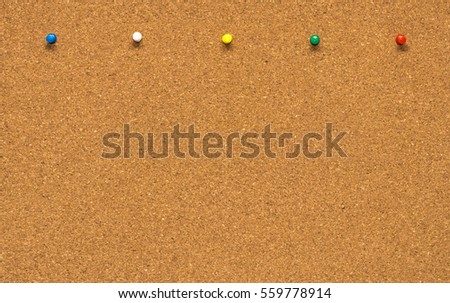 The Group of thumbtacks pinned on corkboard