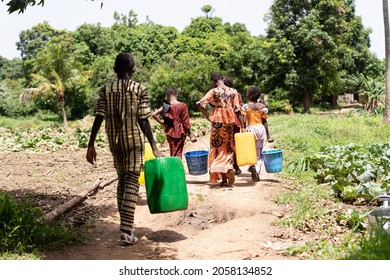 Group Of Tired African School-age Children Busy Carrying Water Back And Forth From The Village Well; Child Labor Concept