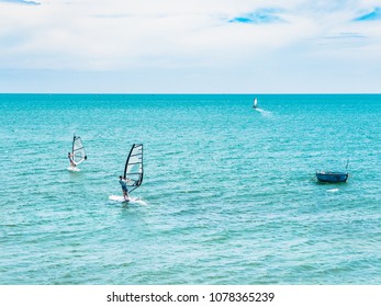 Group Of Touriest Play  Wind Surfing Sport In The Sea Under Vast Blue Sky