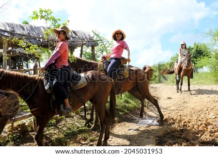 A group of tourists enjoy riding on horses on a trail in rural Trinidad, Cuba. One of the horses is peeing.
