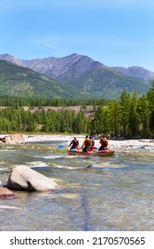 Group of tourists float on an inflatable rubber catamaran down a mountain river on summer sunny day. Rafting as a hobby. Buryatia, Irkut river. Active team pastime concept.  Beautiful landscape