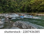 group of tourists rafting on a raft and kayak in the middle of the jungle on the Pacuare River in Costa Rica