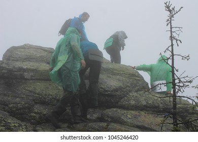 A Group Of Tourists Rises To The Top Of The Mountain In Severe Weather Conditions. Atmospheric Photo With Climbers In The Ural Mountains. National Park 