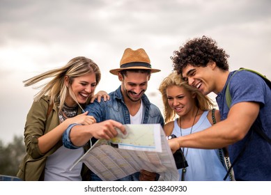 Group of tourists searching for places on their map outdoors. - Shutterstock ID 623840930