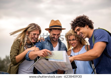 Group of tourists searching for places on their map outdoors.