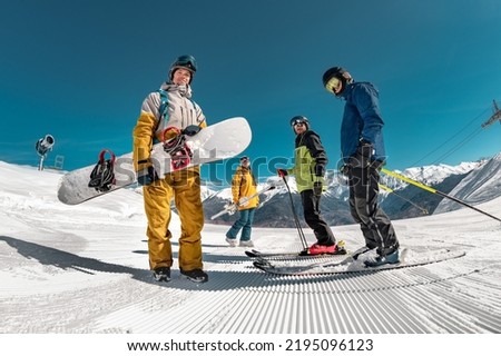 Group of tourists skiers and snowboarders stands at ski resort. Winter sports concept