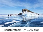 A group of tourists travels along the ice of the frozen Lake Baikal. Excursion to the beautiful iced rocks of Horin-Irgi or Cape Kobyliya Golova