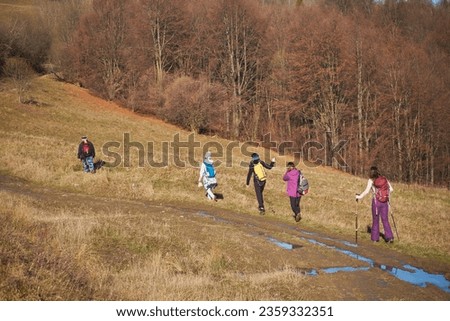 A group of tourists walks among the autumn mountain landscape