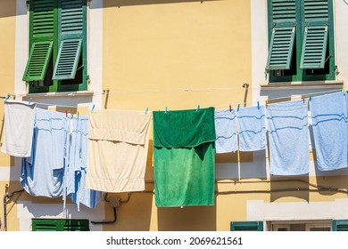 Group of towels and bathrobes hanging outside the window on a clothesline to dry in the sun. Tellaro village, Liguria, Italy, southern Europe. - Powered by Shutterstock