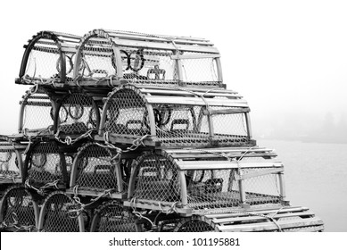 A group of traditional lobster traps sit on a Nova Scotia pier in dense fog.