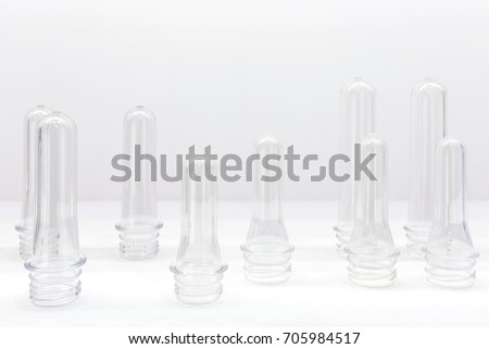 group of transparent plastic PET preforms are displayed on the shelf in white background. industrial concept. selective focus.