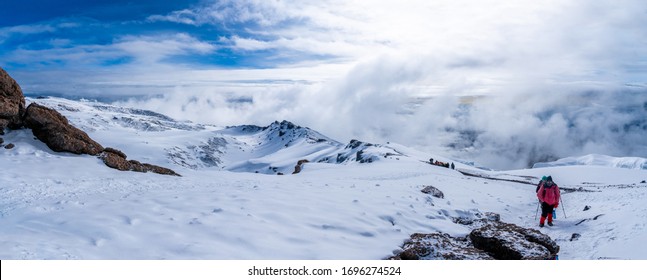 Group of trekkers hiking among snows and rocks of Kilimanjaro mountain