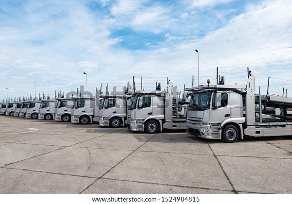 Group of trucks parked in line\
at truck stop. Car transporters in row. Transportation\
services.