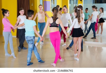 Group of tweens exercising folk dance, forming circle with female coach in choreography class - Shutterstock ID 2146886741