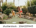 Group of two funny kids playing mini golf, children enjoying summer vacation