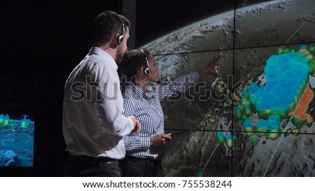 Group of two scientists observing and tracking hurricane on map and analyzing weather. Elements of this image furnished by NASA.