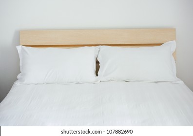 Group Of Two White Pillows On A Bed With Headboard.