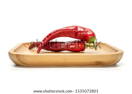 Group of two whole fresh hot pepper on wooden square plate isolated on white background