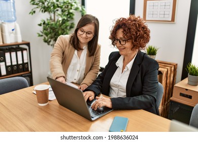 Group of two women working at the office. Mature woman and down syndrome girl working at inclusive teamwork.