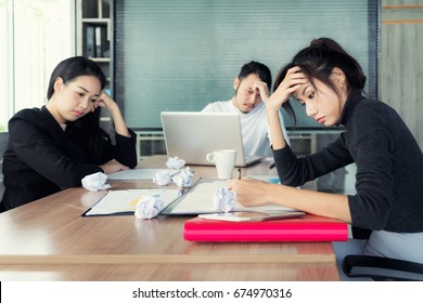 Group Of Unhappy Asian Business People In Casual Suit Sitting In Business Meeting Room And Looking Strain.