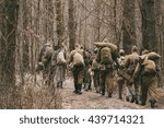 Group Of Unidentified Re-enactors Dressed As World War II Russian Soviet Soldiers In Camouflage Walks Through Forest.