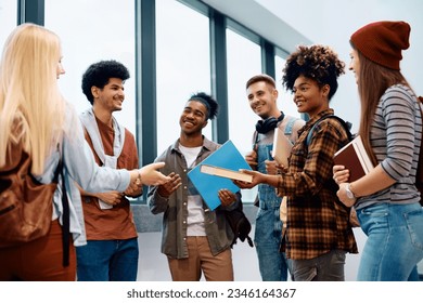 Group of university students after a lecture in a hallway. Focus is on African American student giving a book to her friend. - Shutterstock ID 2346164367