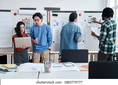 Group Of University Students Is Writing On A Whiteboard And Talking While Their Group Mates Discussing Something And Looking At The Laptop Screen. Studying At Web Design Faculty Concept