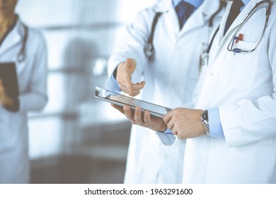 Group of unknown doctors use a computer tablet to check up some medical names records, while standing in a hospital office. Physicians ready to examine and help patients. Medical help, insurance in - Shutterstock ID 1963291600