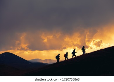 Group of unrecognizable hikers are walking at majestic sunset in mountains