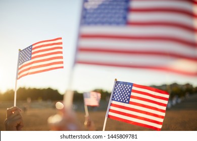 Group Of Unrecognizable People Waving Small American Flags On Sticks At Parade Outdoors