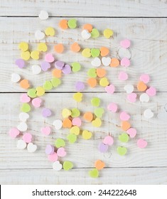 A Group Of Valentine's Candy Hearts Scattered In A Random Pattern On A Rustic Whitewashed Wood Table. Overhead Shot In Square Format.