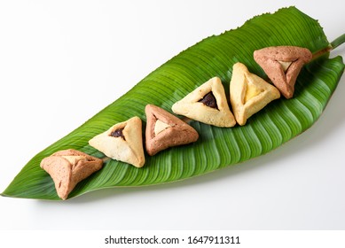 Group Of Variety Cookies Traditional Meal For Jewish Holiday Purim On Palm Leaf. Hamantaschen Triangular Pastries Also Called Haman's Pockets Or Oznei Haman-Haman's Ears.