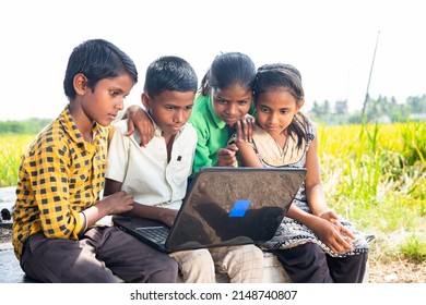 group of village kids busy using laptop near paddy field - conept of online education, technology and learning.
