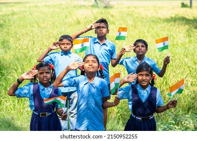 Group of village school children with Indian flag in hand saluting by looking above during flag hosting - concept of independence or republicday celebration