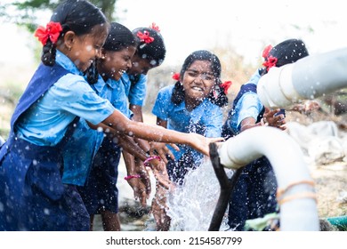 group of village school girl kids playing in water near paddy field - concept of happiness, fun and carefree lifestyle