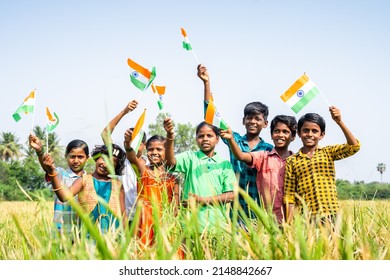 Group Of Village Teenage Kids Waving Indian Flag By Looking At Camera At Paddy Filed - Concept Of Independence Or Republic Day Celebration, Freedom And Friendship.