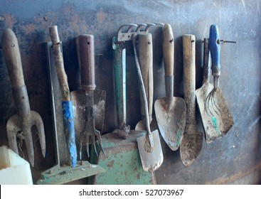 Group Of Vintage Dirty Farm Metal Garden Tools As Shovels And Rakes Are Waiting For Work On The Wall