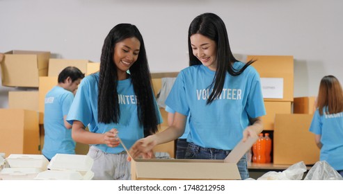 Group Of Volunteer People Preparing Free Food Delivery For Poor People During Covid19. As Charity Workers And Members Of The Community Work Together Filling Boxes With Food.