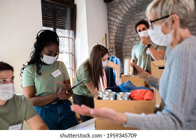 Group Of Volunteers With Face Mask Working In Community Charity Donation Center.