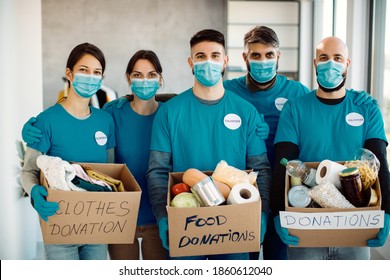 Group Of Volunteers Wearing Protective Face Masks And Holding Donation Boxes While Looking At Camera. 