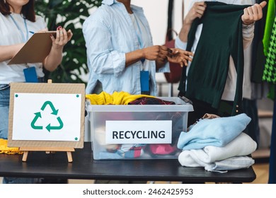 Group of volunteers, young women and man, sorting clothes in charitable foundation for charity donation, recycling. Concept of textile pollution, conscious consumption. Ecology, sustainable lifestyle - Powered by Shutterstock