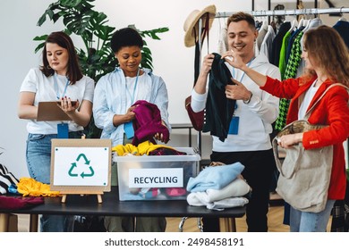 Group of volunteers, young women and man, sorting clothes in charitable foundation for charity donation, recycling. Concept of textile pollution, conscious consumption. Ecology, sustainable lifestyle - Powered by Shutterstock