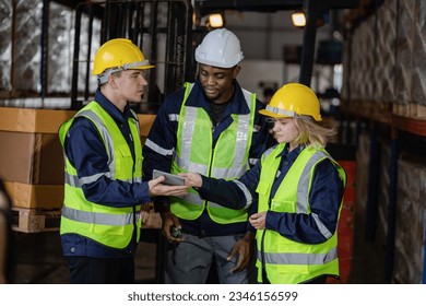 Group of warehouse employees using a digital warehouse management system. logistics manager using a digital tablet while having a meeting with his team.