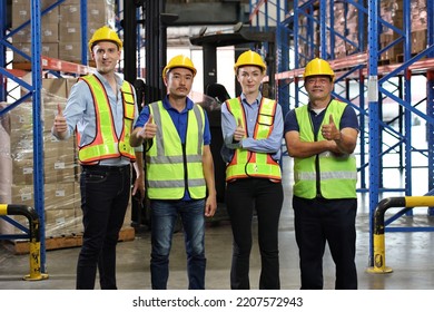 Group Of Warehouse Workers With Hardhats And Reflective Jackets Standing And Showing Thumb Up Celebrate Successful Or Completed Deal Commitment At Retail Warehouse Logistics, Distribution Center