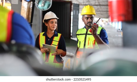 Group Of Warehouse Workers With Hardhats And Reflective Jackets Using Tablet, Walkie Talkie Radio And Cardboard While Controlling Stock And Inventory In Retail Warehouse Logistics, Distribution Center