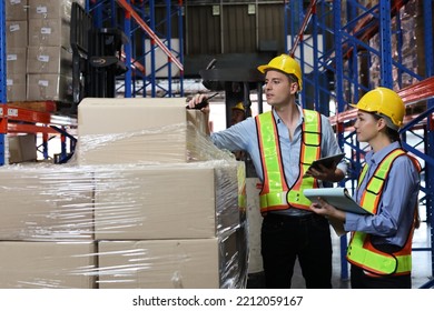 Group Of Warehouse Workers With Hardhats And Reflective Jackets Using Tablet, Walkie Talkie Radio And Cardboard While Controlling Stock And Inventory In Retail Warehouse Logistics, Distribution Center