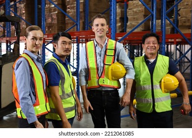 Group Of Warehouse Workers With Hardhats And Reflective Jackets Standing And Looking Camera With Confident Celebrate Successful Together Or Completed Deal At Retail Warehouse Logistics Center